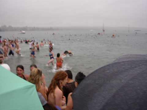 Swimmers in eccentric outfits running into English Bay