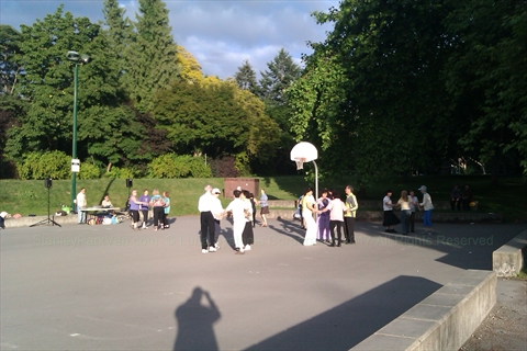 Spectators looking on from concrete benches while music plays
