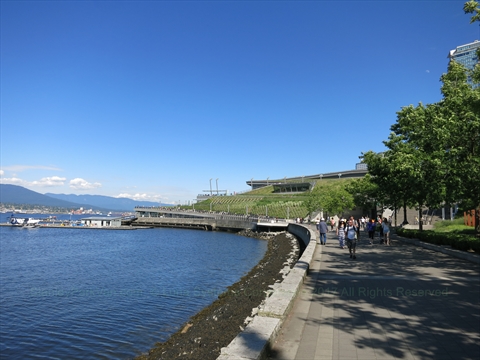 Pedestrians walking along the paved waterfront Coal Harbour Seawall path