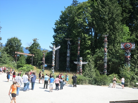 Looking up at cedar carvings with mature tree canopies behind