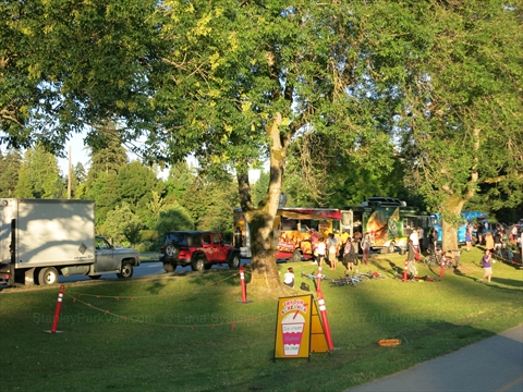 Local food trucks parked near the lawn perimeter for movie snacks