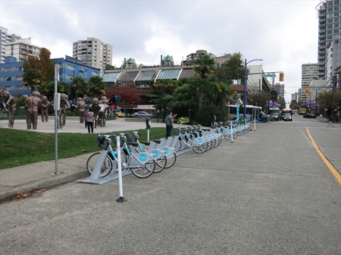 A row of silver municipal Mobi bike share docks positioned at English Bay beach