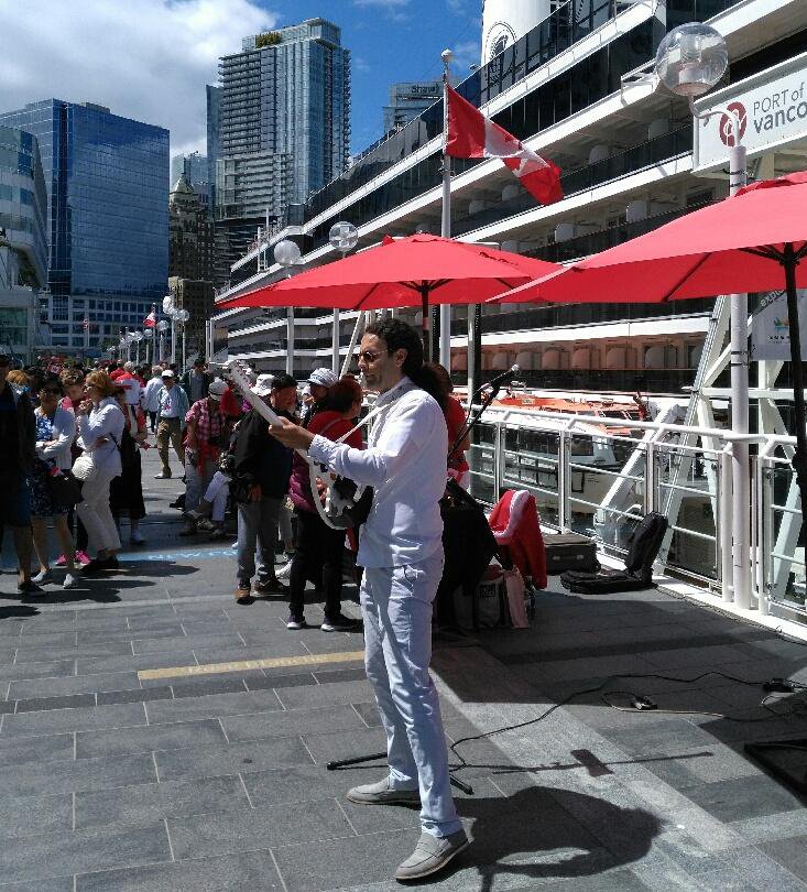 Family crowds wandering past the Canada Place white sails flags