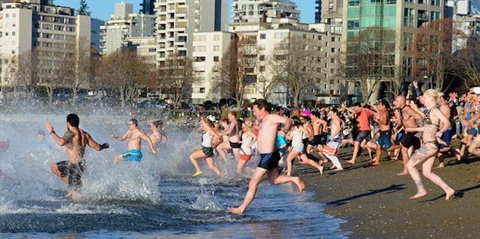 Swimmers celebrating the Polar Bear Swim at English Bay near Stanley Park, Vancouver, BC, Canada